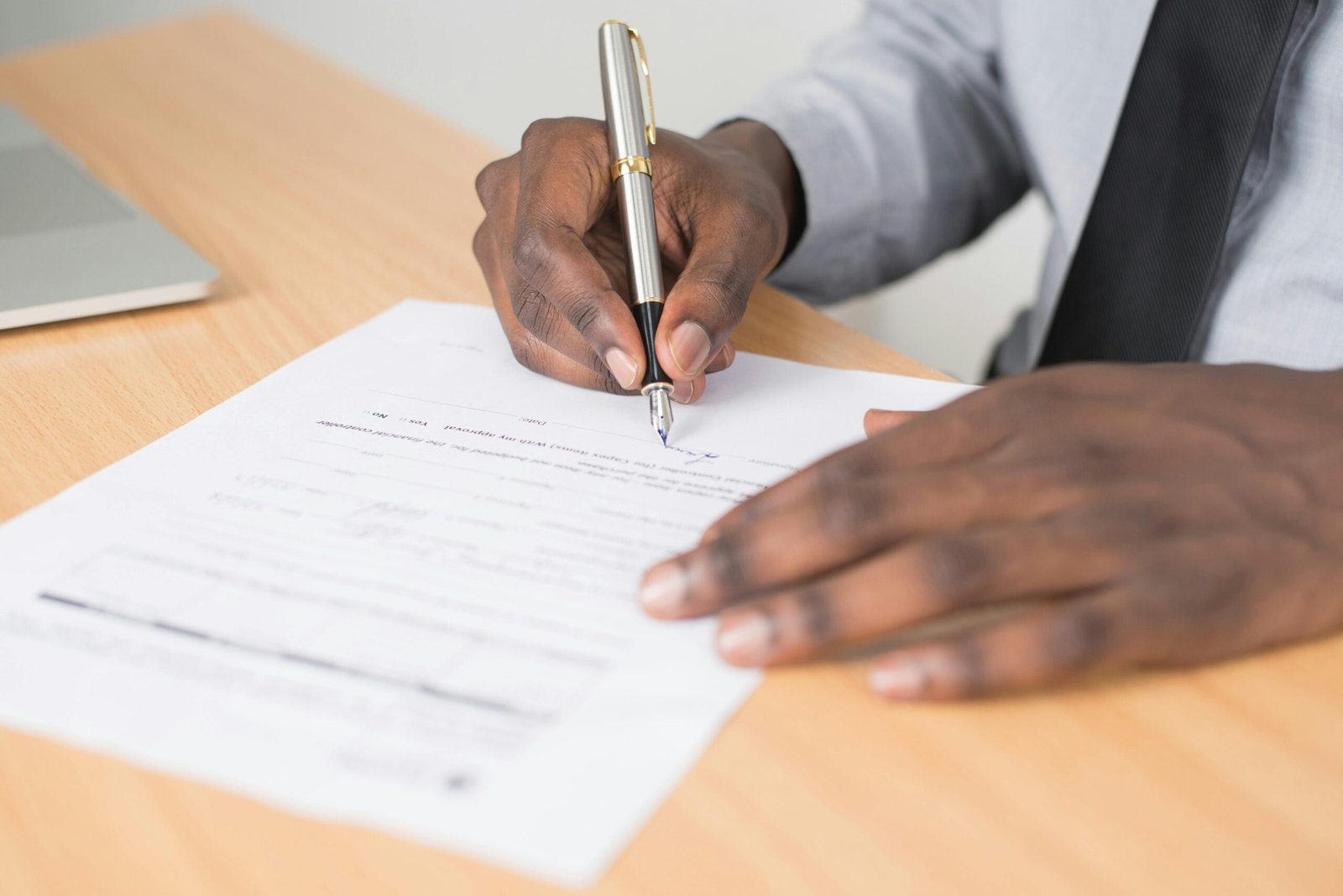 Close-up of a businessman signing a contract at an office desk.